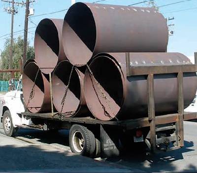 A truck with four large pipes on the back.